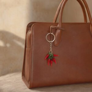 Bijou Alaia 5 piments rouges en verre sur sac marron
